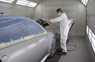 Technician spray-painting a panel in the Garmat downdraft bake paint booth at River Valley Collision